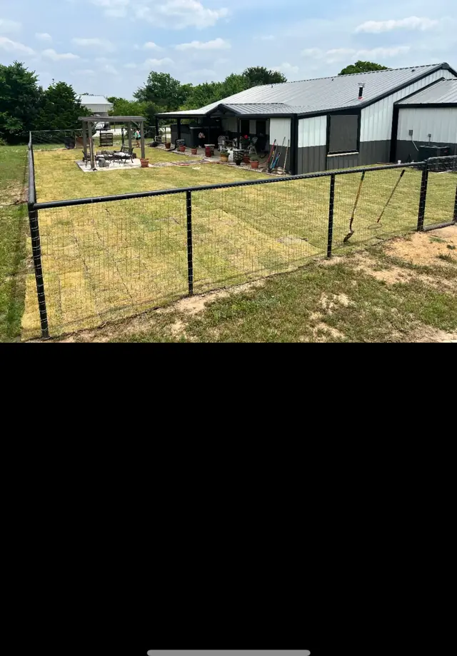 Metal building beyond a fenced pasture