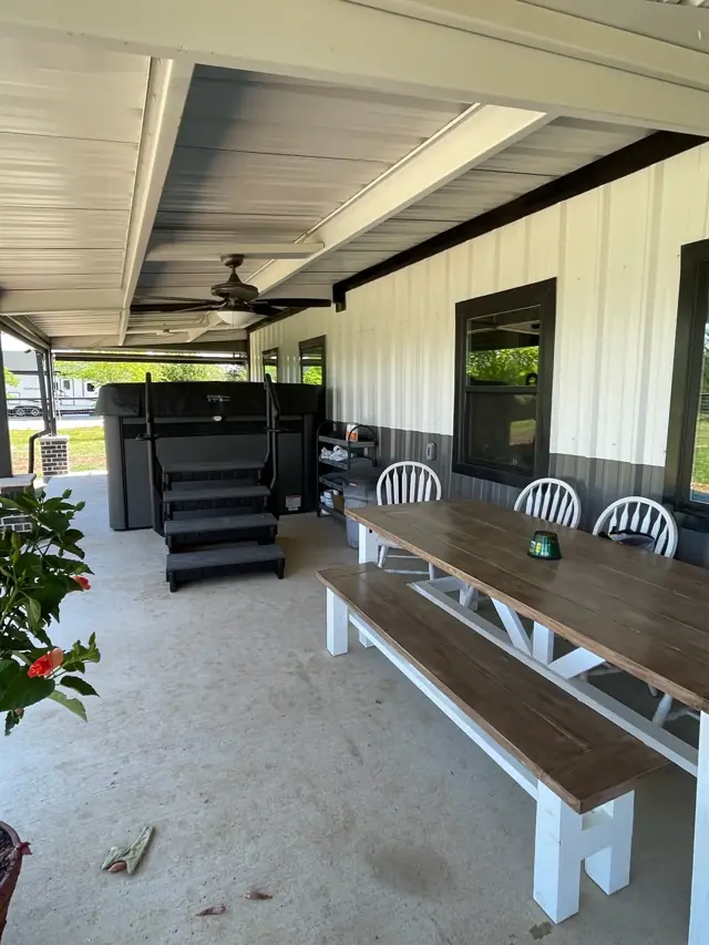 Covered patio with a ceiling fan and long bench table