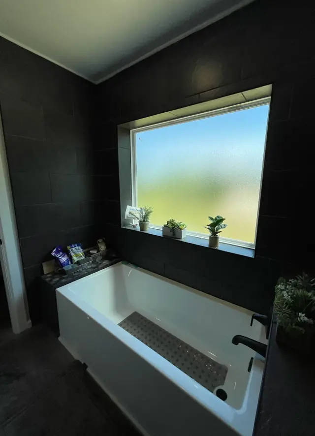 Soaking tub under a window with dark walls
