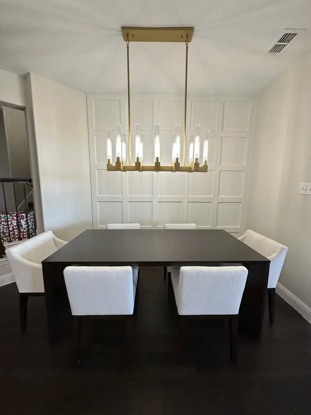 Dining room with a paneled accent wall and linear chandelier