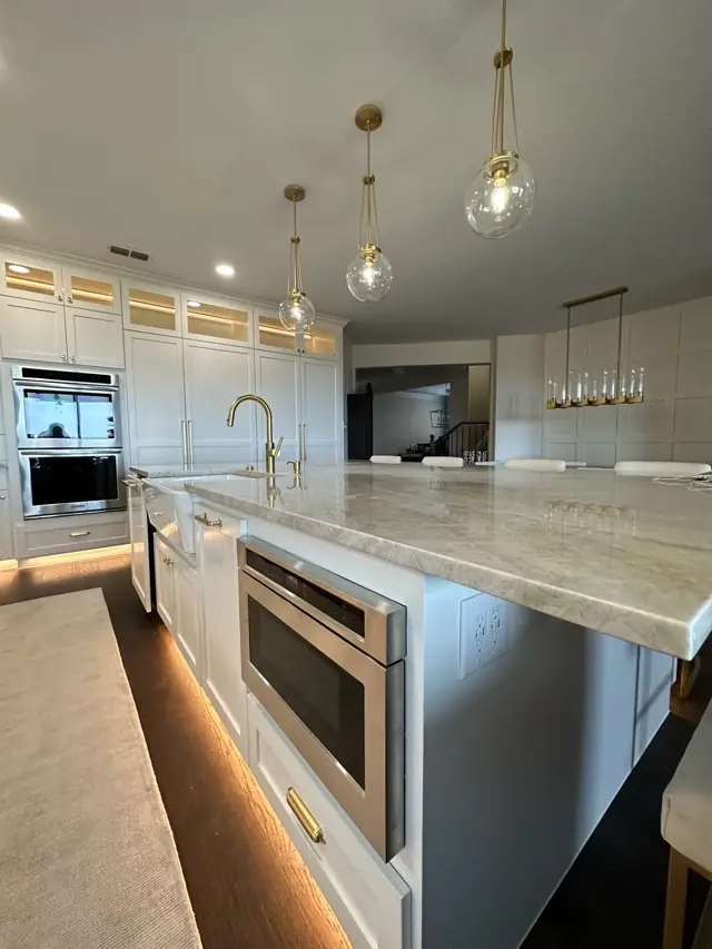 White kitchen with pendant lights, built-in microwave drawer, and lit toe-kick