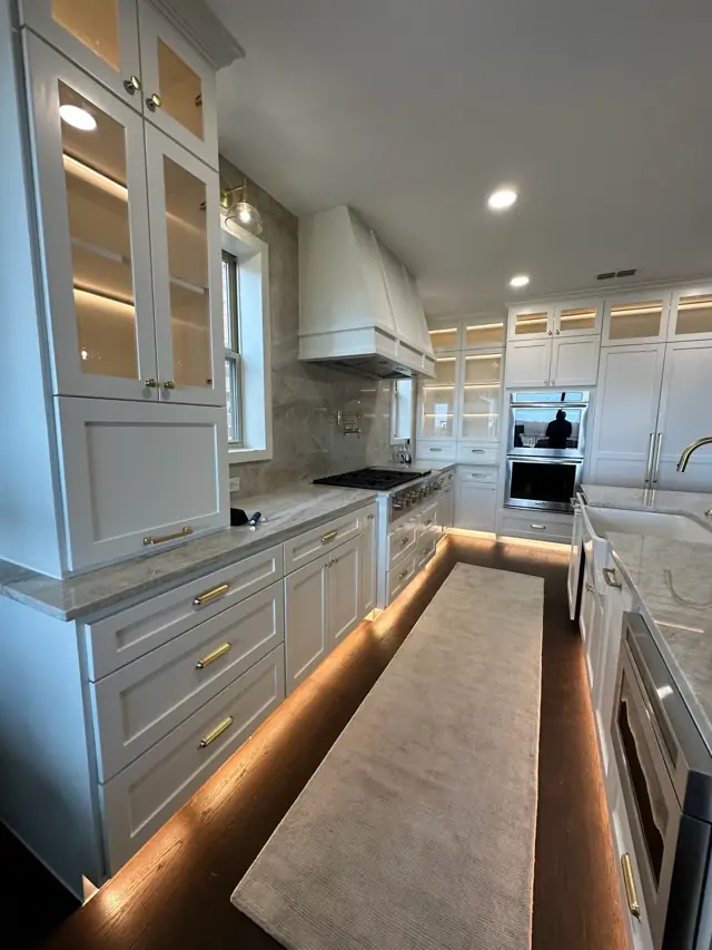 White cabinetry with glass uppers and a glowing toe-kick