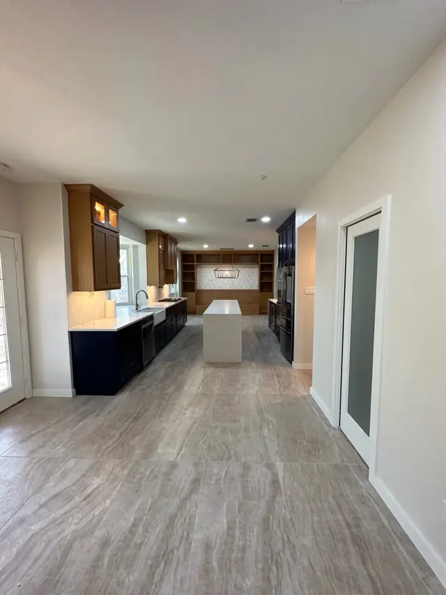 Hallway view into a kitchen with navy cabinetry and wood-look floors