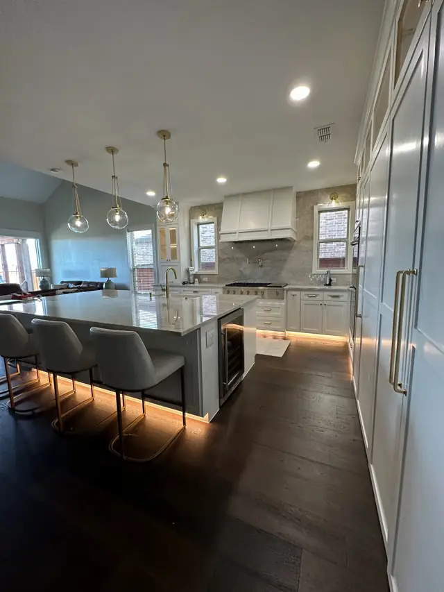 Open kitchen with a long island, bar stools, and under-cabinet lighting