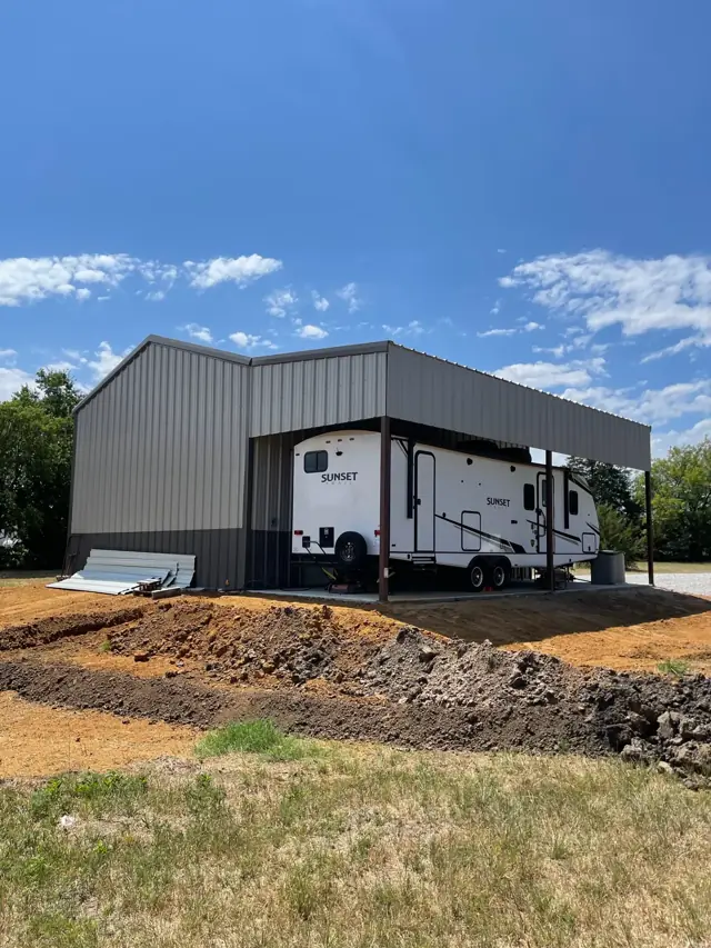 Metal building with an RV parked under the lean-to