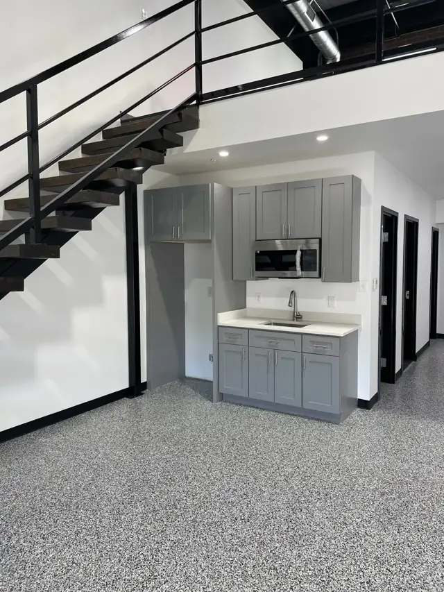 Open steel stair, kitchenette, and epoxy floor in a loft unit
