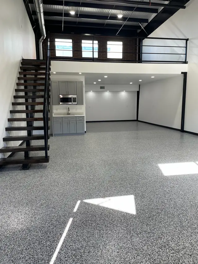 Loft unit with a mezzanine, open steel stair, and epoxy floor
