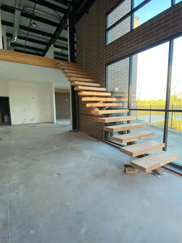 Open-tread wood stair beside a glass storefront wall