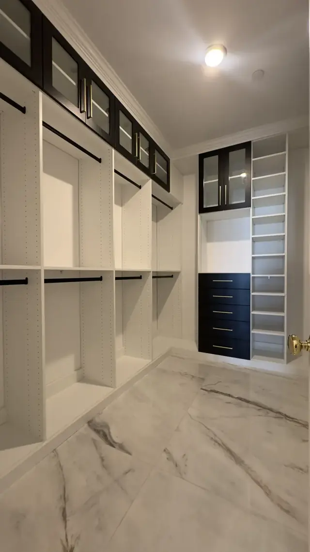 Closet with white built-in shelving and marble-look floors