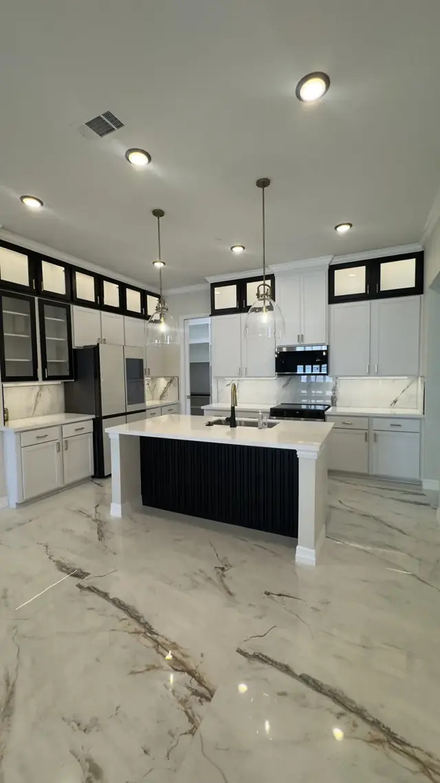 White kitchen with a black-base island and marble-look floors