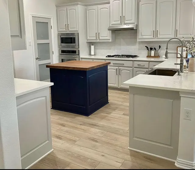 White kitchen with a navy island and butcher-block top