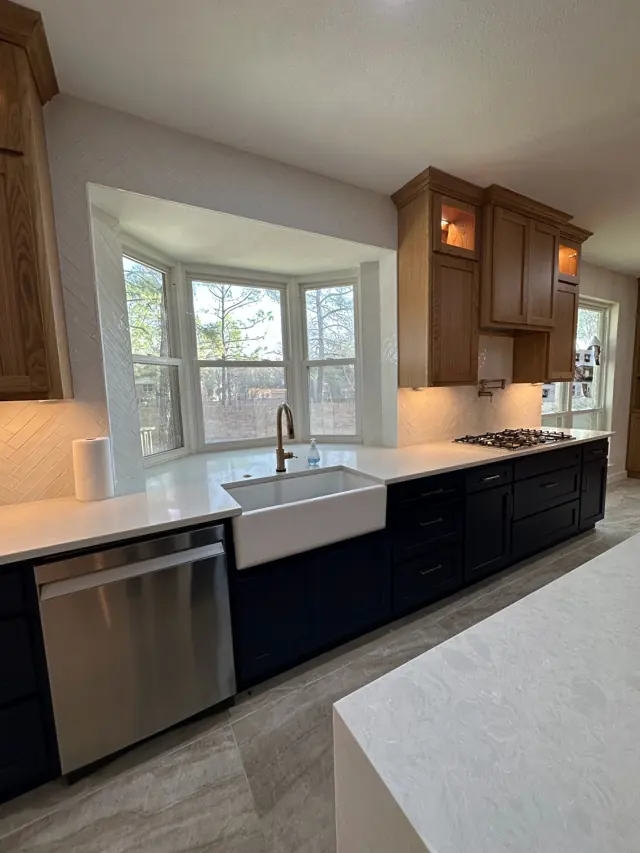 Kitchen with navy lowers, oak uppers, farmhouse sink, and herringbone backsplash